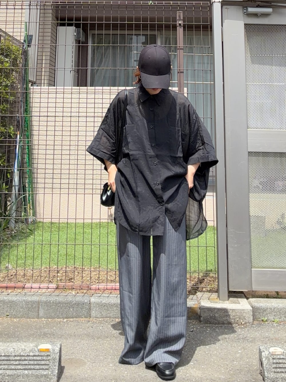 ブラック系のシャツ/ブラウス、グレー系のスラックス、ブラック系の財布を着用したレディースの春コーディネートの2枚目の写真