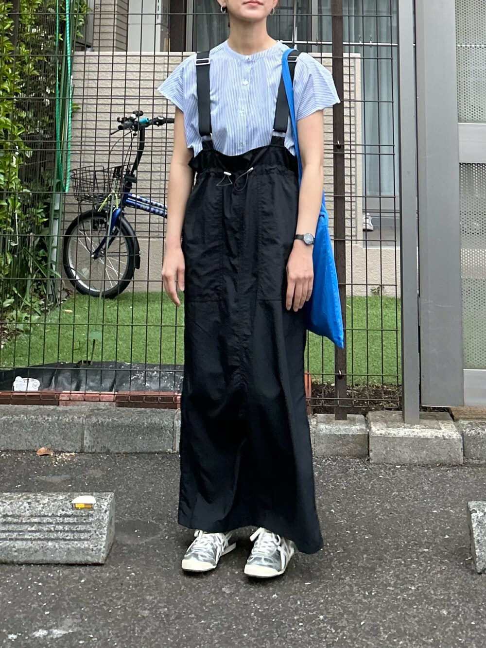 ブルー系のシャツ/ブラウス、ブラック系のジャンパースカート、シルバー系のスニーカーを着用したレディースの春コーディネートの2枚目の写真