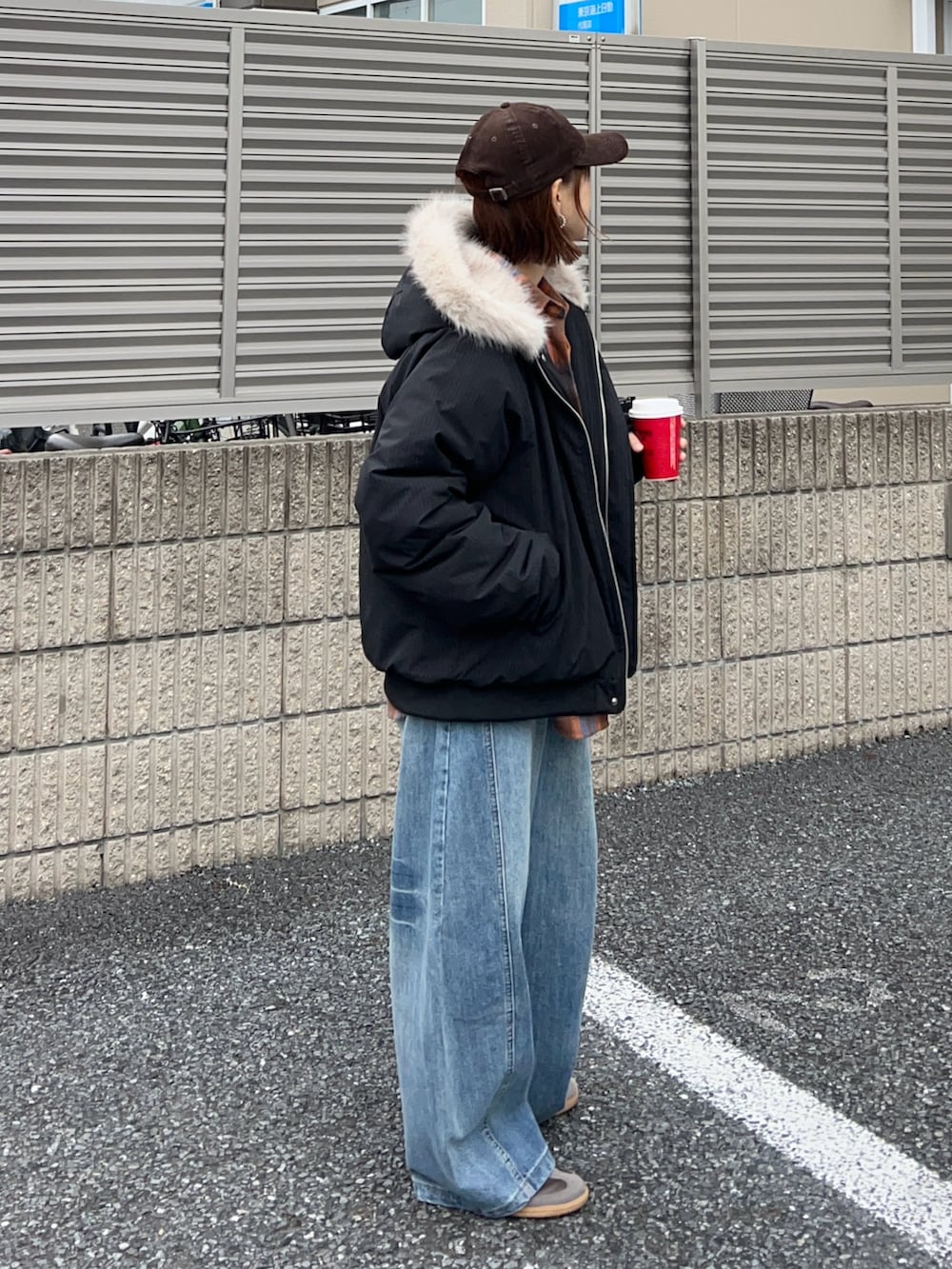 オレンジ系のショルダーバッグ、ブラウン系のスニーカー、ブラック系のその他アウターを着用したレディースの冬コーディネートの3枚目の写真