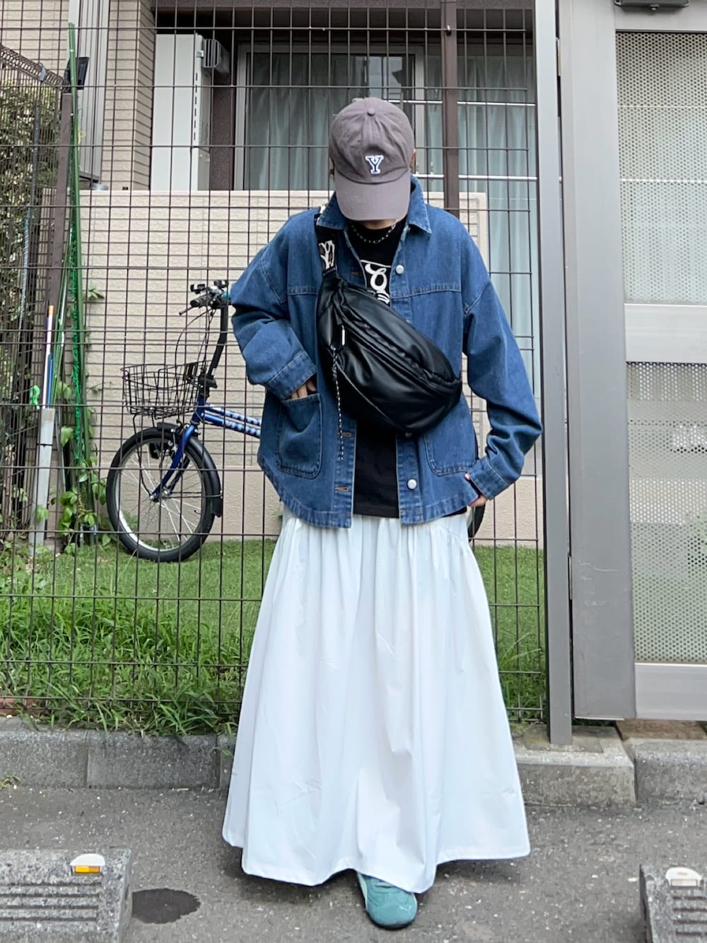 ブルー系のデニムジャケット、ブラック系のボディバッグ/ウエストポーチ、グリーン系のスニーカーを着用したレディースの秋コーディネートの3枚目の写真