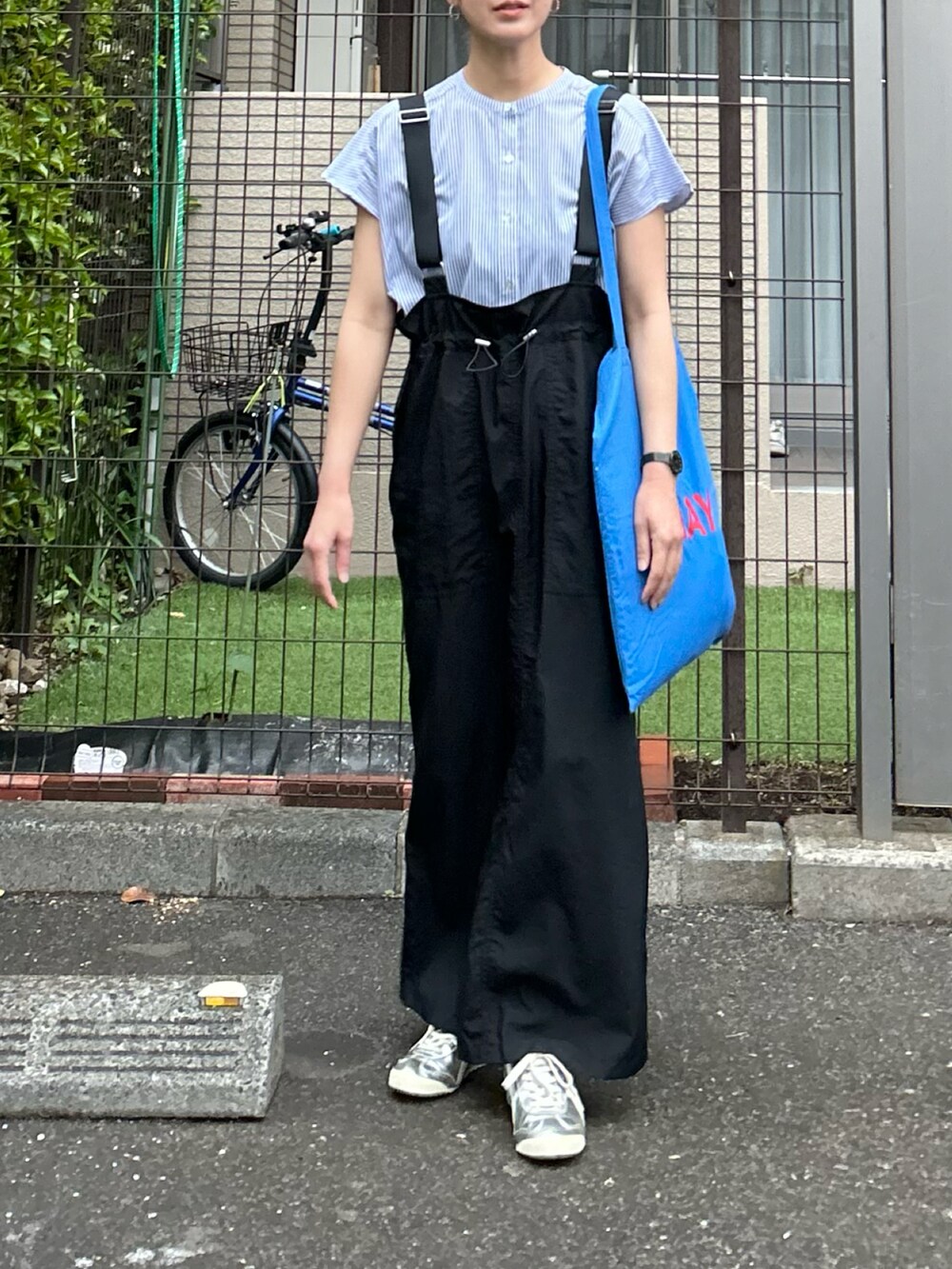 ブルー系のシャツ/ブラウス、ブラック系のジャンパースカート、シルバー系のスニーカーを着用したレディースの春コーディネートの3枚目の写真