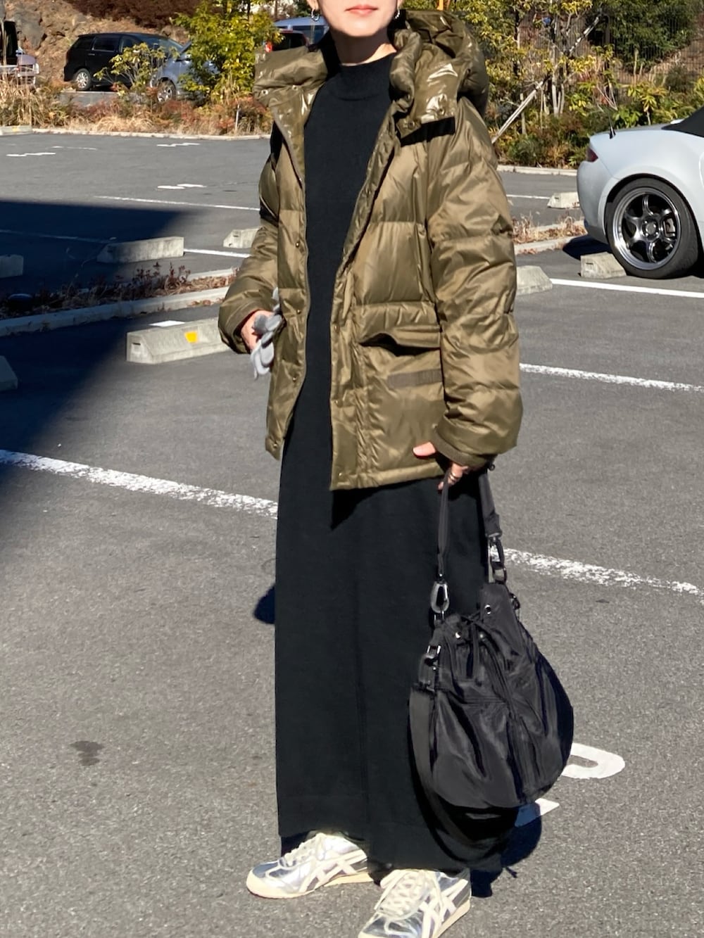 グリーン系のダウンジャケット/コート、ブラック系のワンピース、ブラック系のショルダーバッグを着用したレディースの冬コーディネートの3枚目の写真