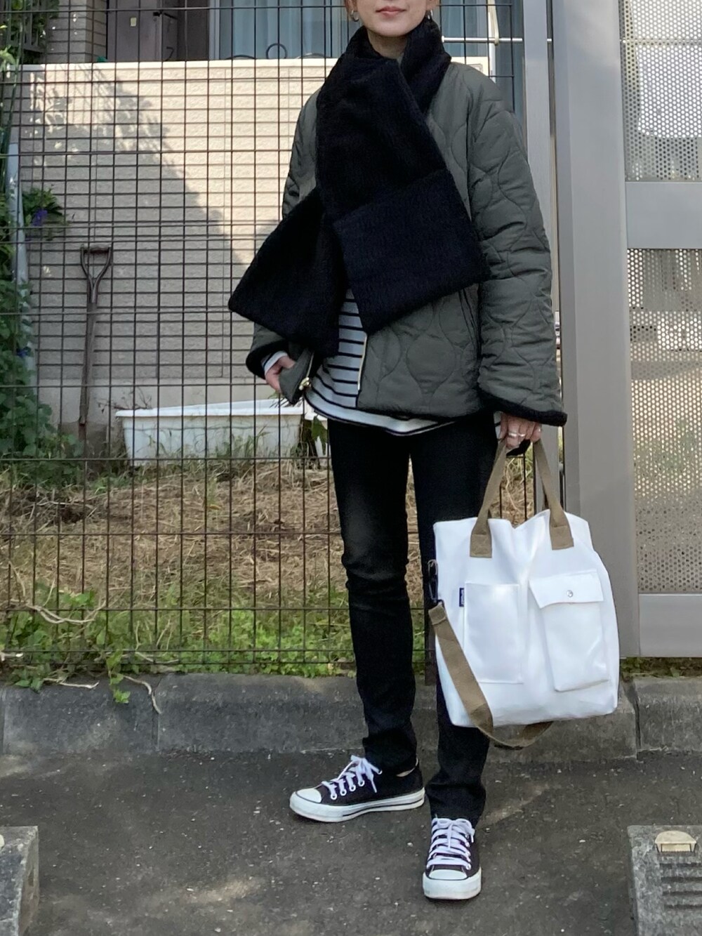 グリーン系のノーカラーコート、ホワイト系のトートバッグ、シルバー系のピアス（両耳用）を着用したレディースの秋コーディネートの2枚目の写真