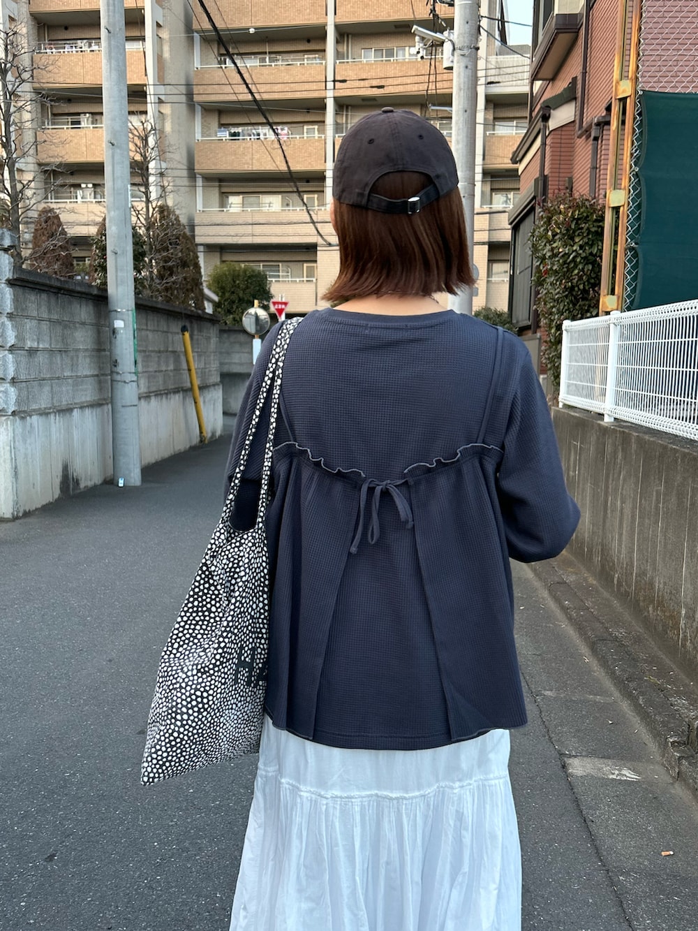 ホワイト系のスカート、グレー系のアンサンブル、イエロー系のスニーカーを着用したレディースの冬コーディネートの5枚目の写真