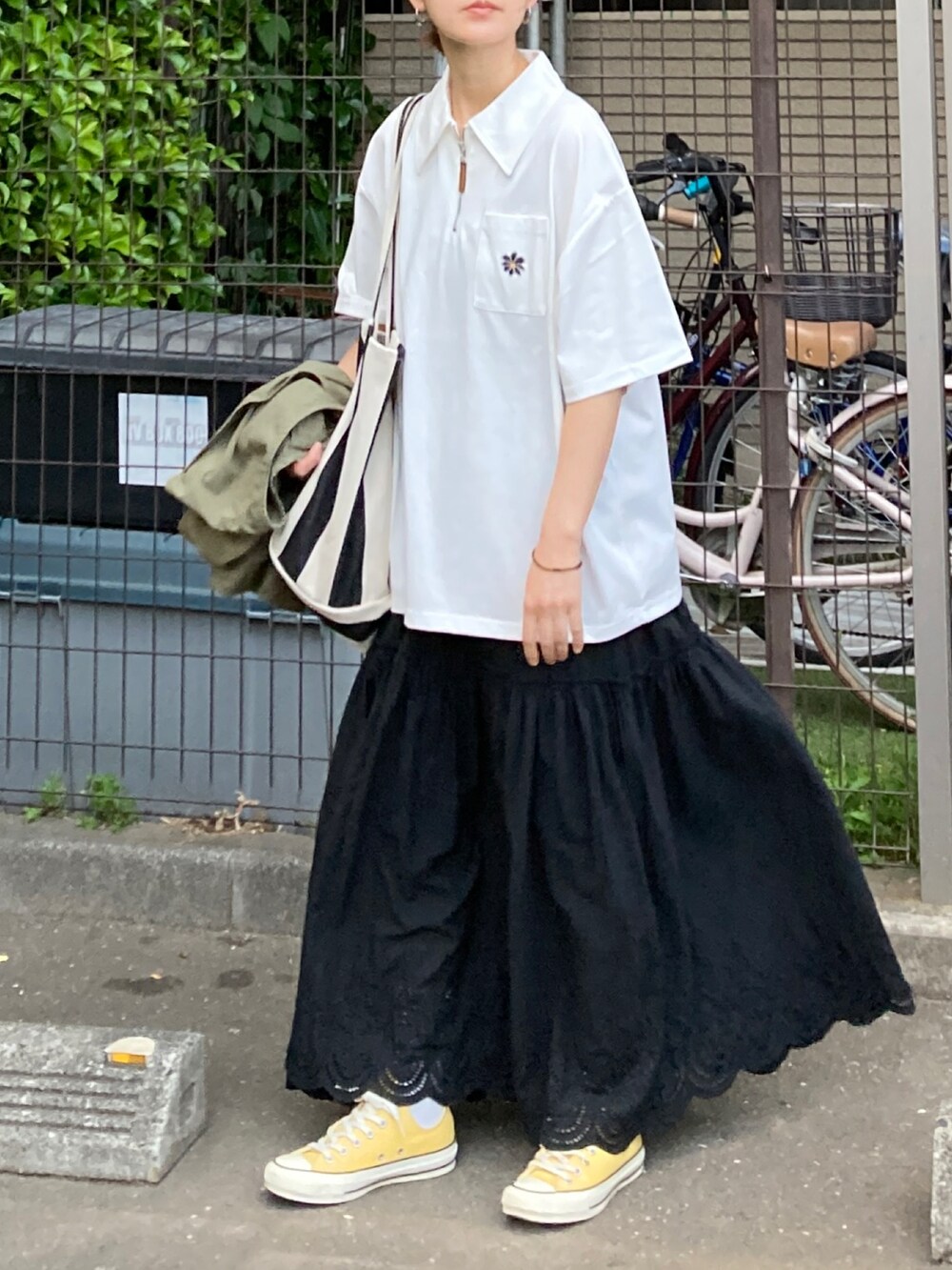 ブラック系のスカート、ブラック系のトートバッグ、イエロー系のスニーカーを着用したレディースの春コーディネートの2枚目の写真