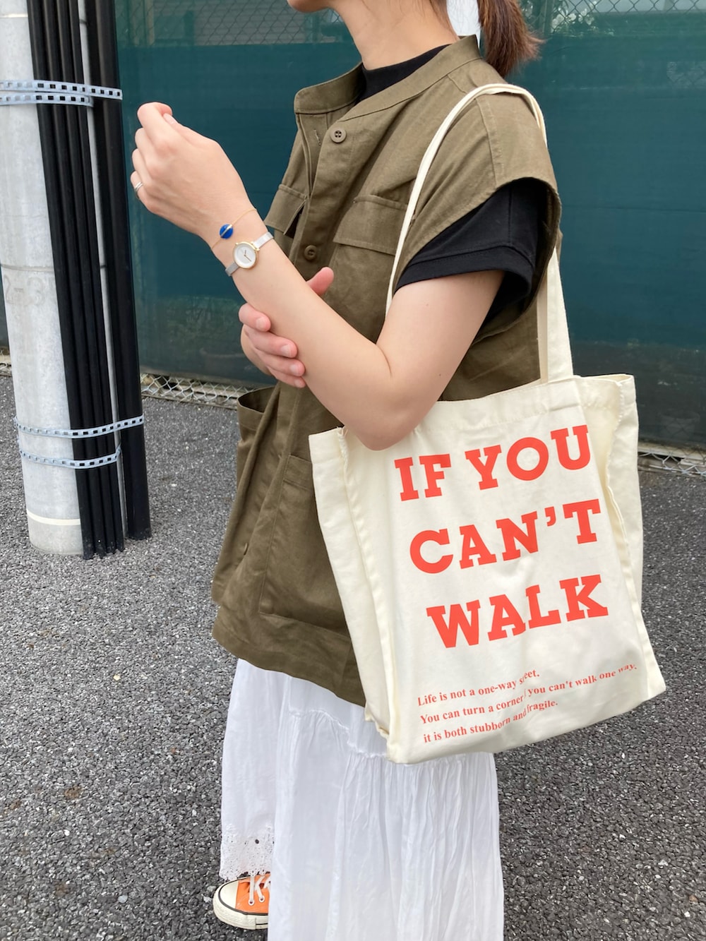 グリーン系のベスト、ブラック系のTシャツ/カットソー、ベージュ系のトートバッグを着用したレディースの夏コーディネートの3枚目の写真