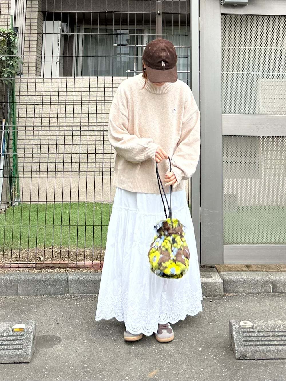ベージュ系のニット/セーター、ホワイト系のスカート、グリーン系のハンドバッグを着用したレディースの秋コーディネートの3枚目の写真