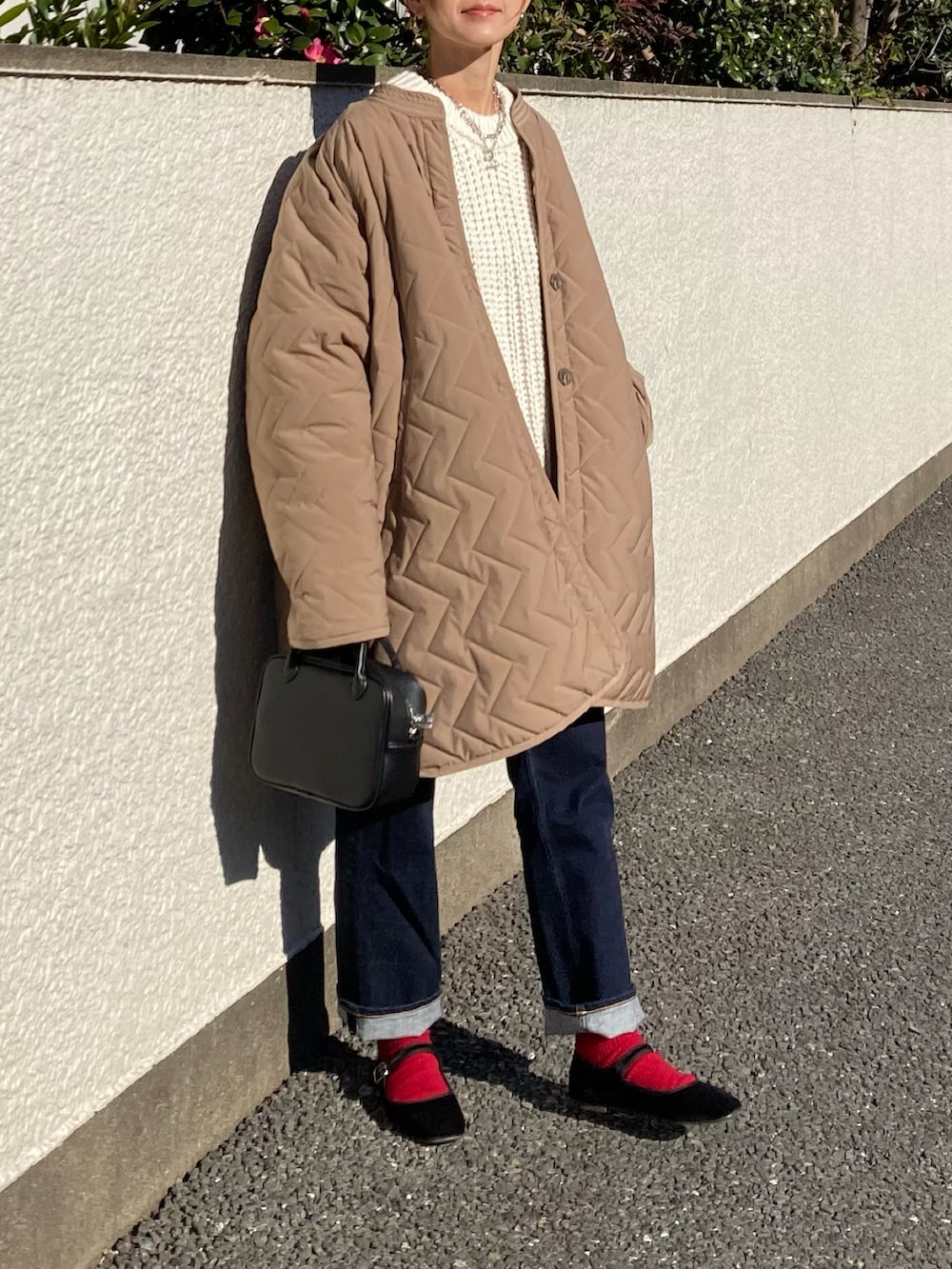 ベージュ系のダウンジャケット/コート、ホワイト系のニット/セーター、ブラック系のボストンバッグを着用したレディースの冬コーディネートの2枚目の写真