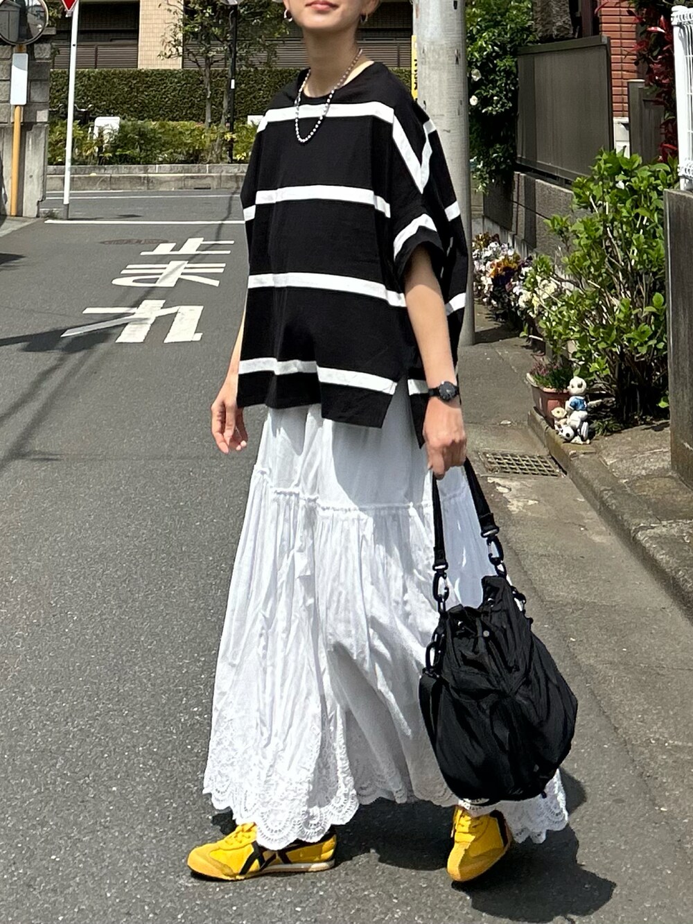 ブラック系のTシャツ/カットソー、ホワイト系のスカート、ブラック系のショルダーバッグを着用したレディースの春コーディネートの2枚目の写真