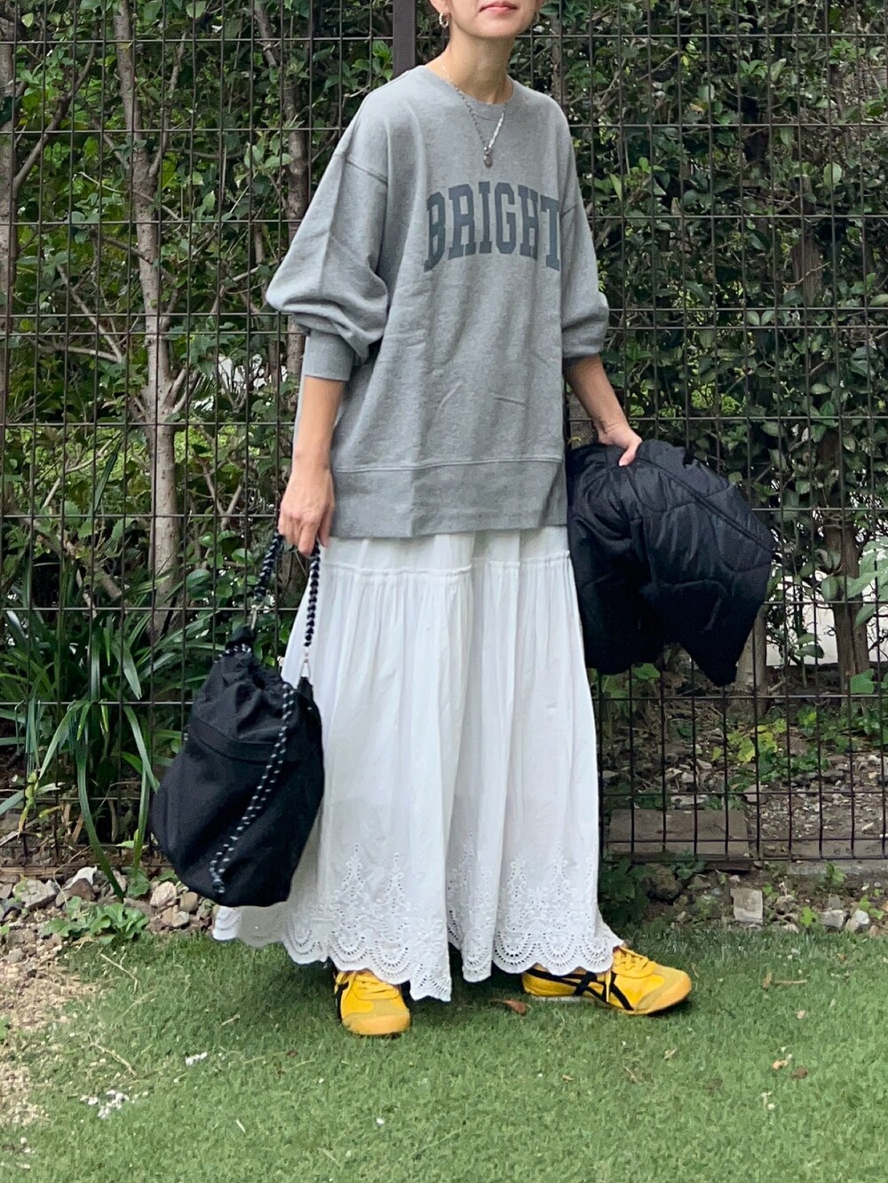 グレー系のスウェット、ホワイト系のスカート、ブラック系のトートバッグを着用したレディースの秋コーディネートの3枚目の写真