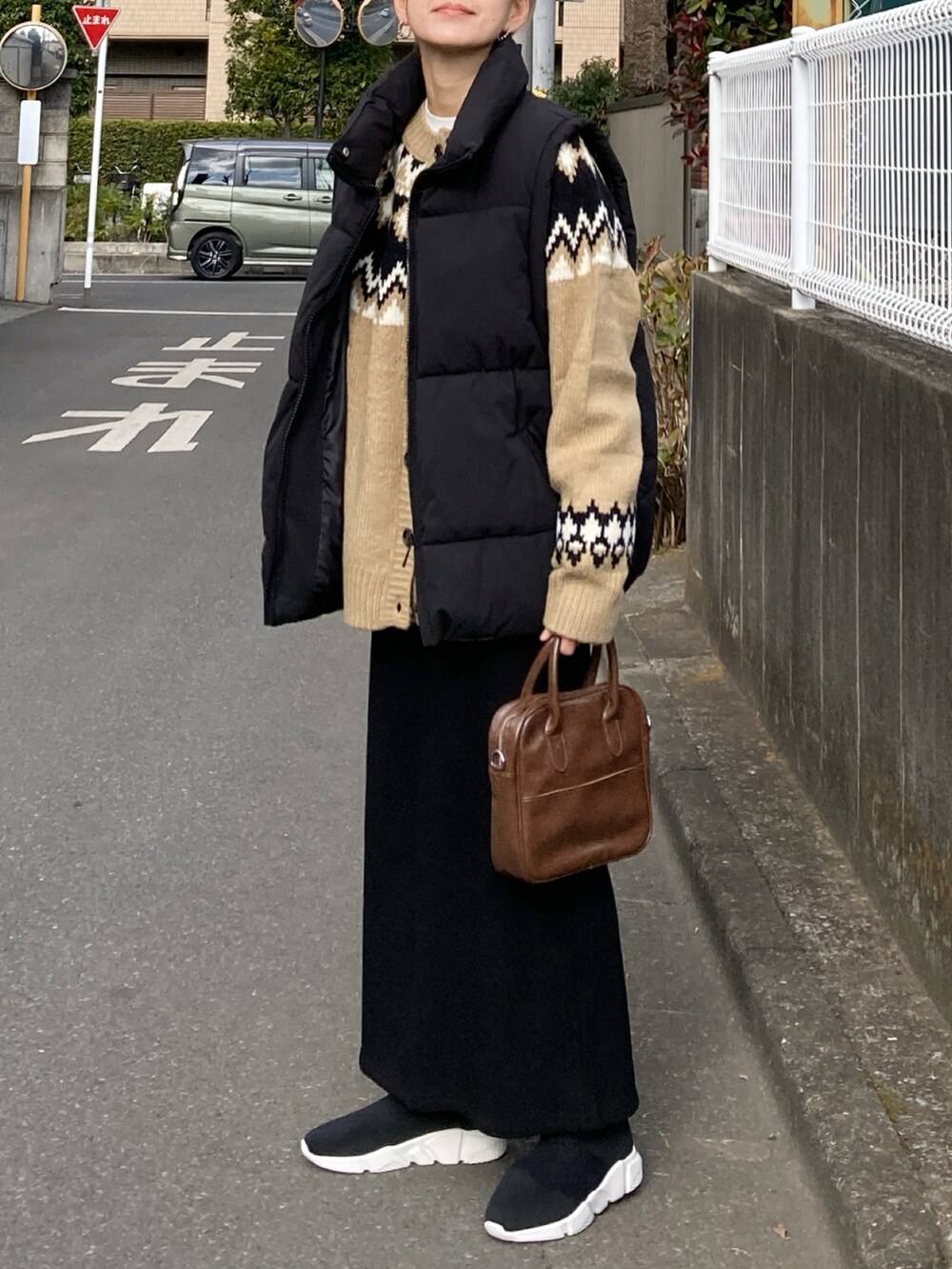 ブラック系のダウンベスト、ベージュ系のニット/セーター、ブラック系のスカートを着用したレディースの冬コーディネートの4枚目の写真