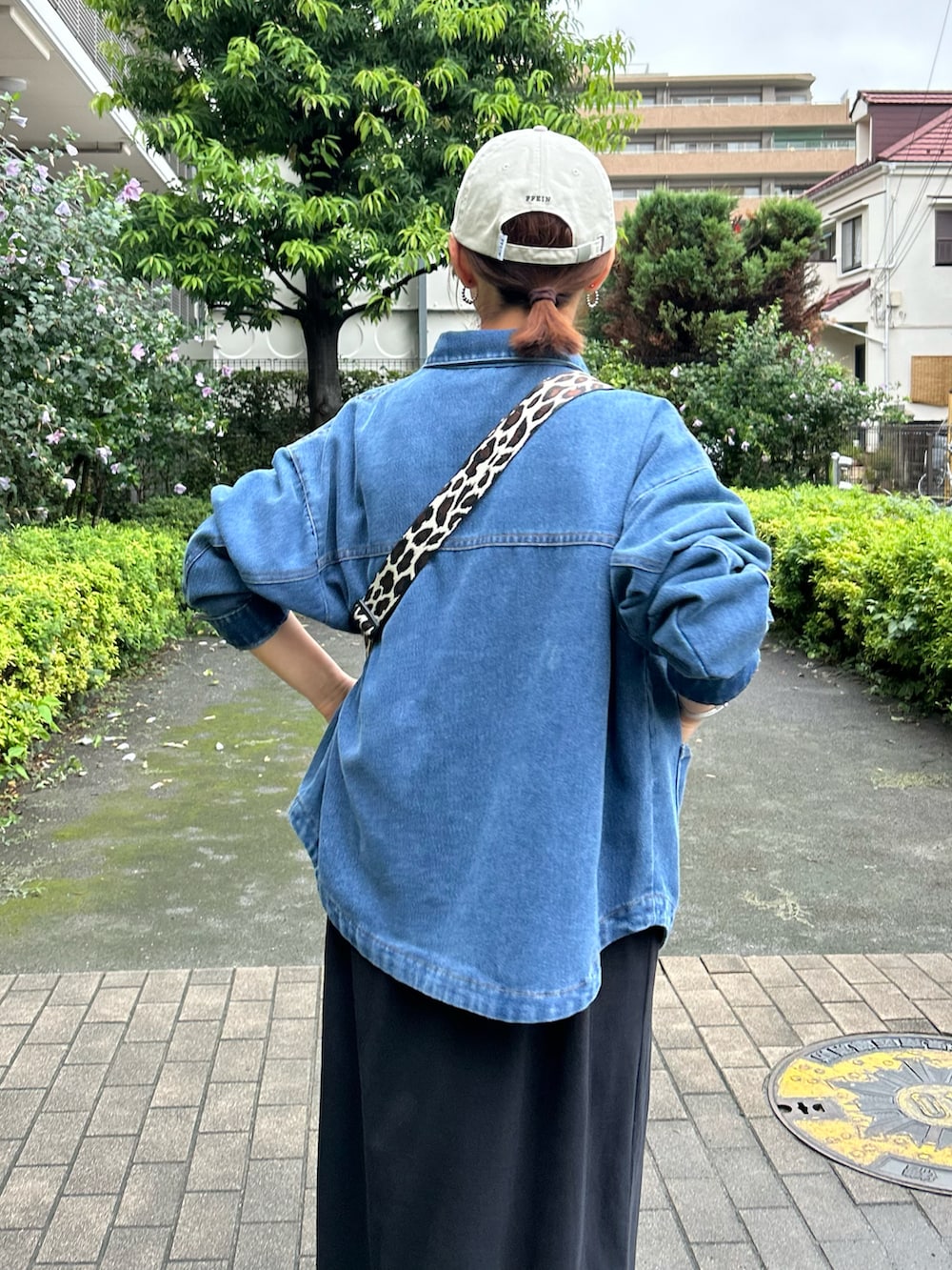 ブラック系のボディバッグ/ウエストポーチ、グリーン系のスニーカー、ブルー系のデニムジャケットを着用したレディースの秋コーディネートの5枚目の写真