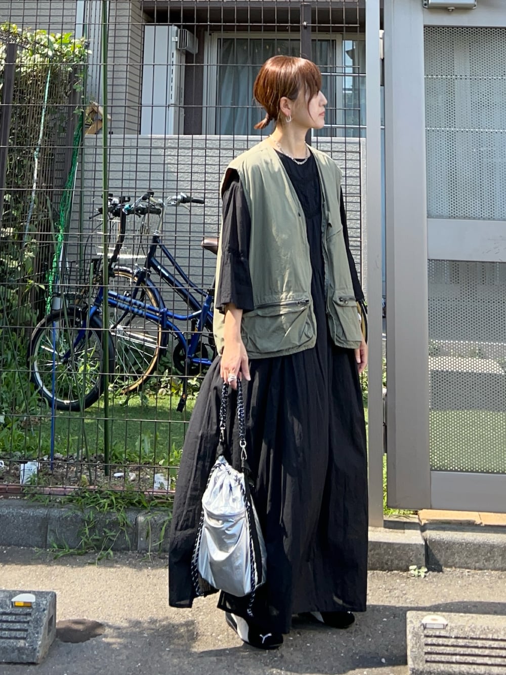 ブラック系のワンピース、シルバー系のトートバッグ、グリーン系のベストを着用したレディースの秋コーディネートの4枚目の写真