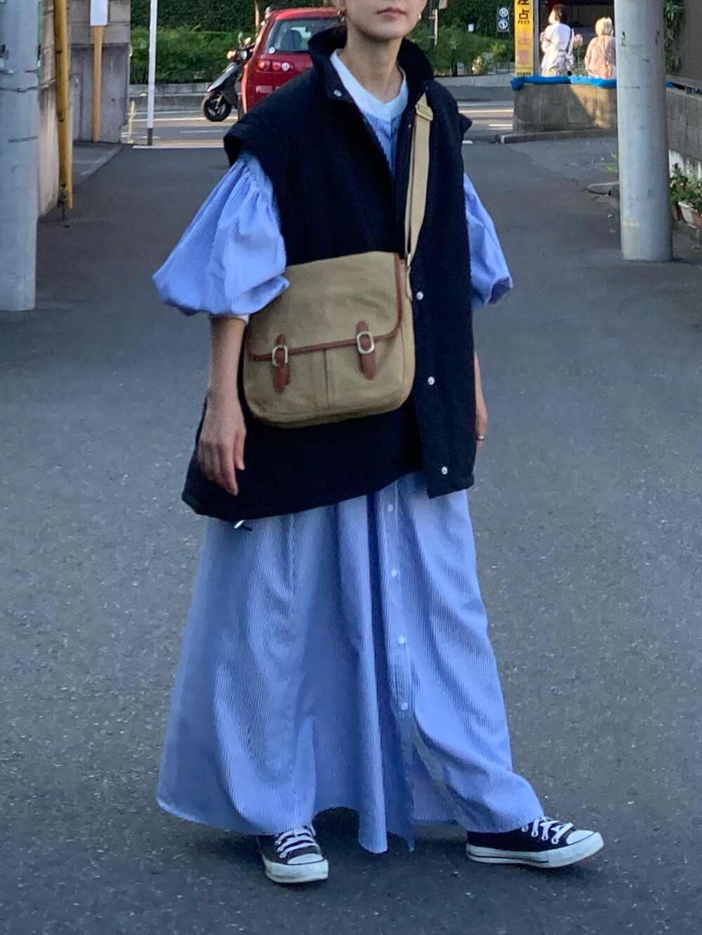 ブラック系のダウンジャケット/コート、ブルー系のワンピース、ベージュ系のショルダーバッグを着用したレディースの秋コーディネートの4枚目の写真