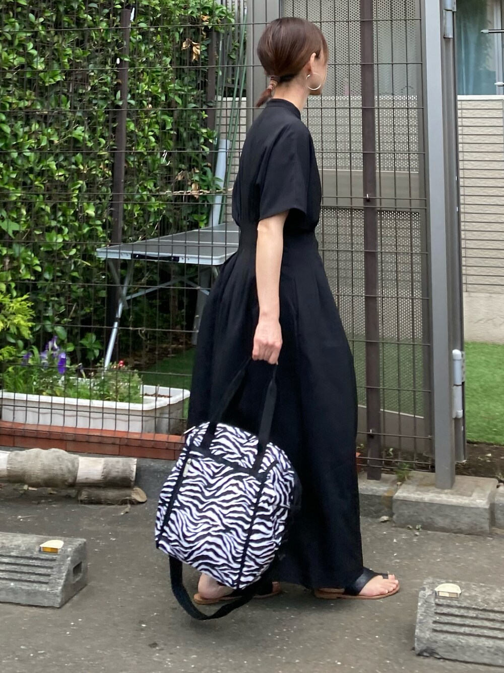 ブラック系のワンピース、ブラック系のトートバッグ、シルバー系のピアス（両耳用）を着用したレディースの夏コーディネートの4枚目の写真