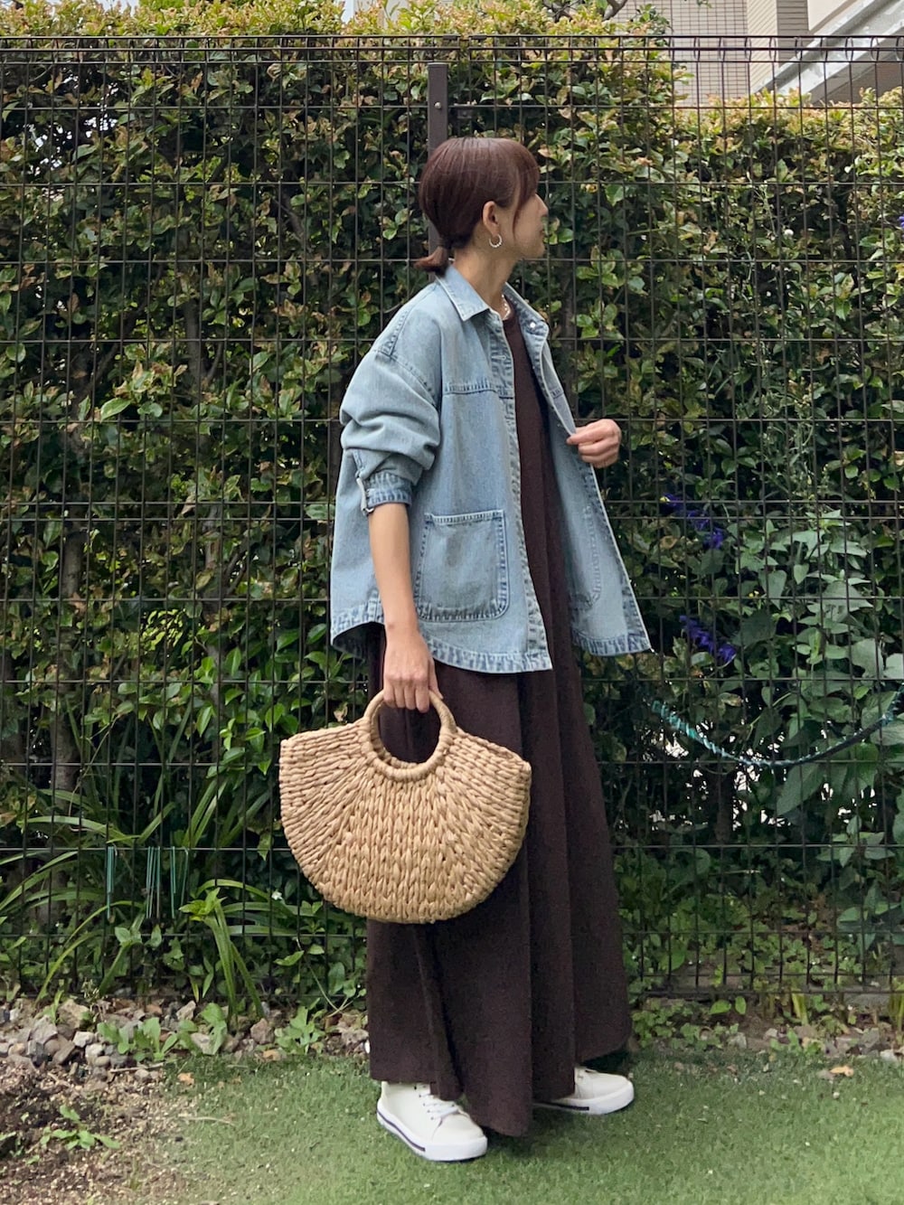 ブルー系のデニムジャケット、ブラウン系のワンピース、ベージュ系のかごバッグを着用したレディースの夏コーディネートの4枚目の写真