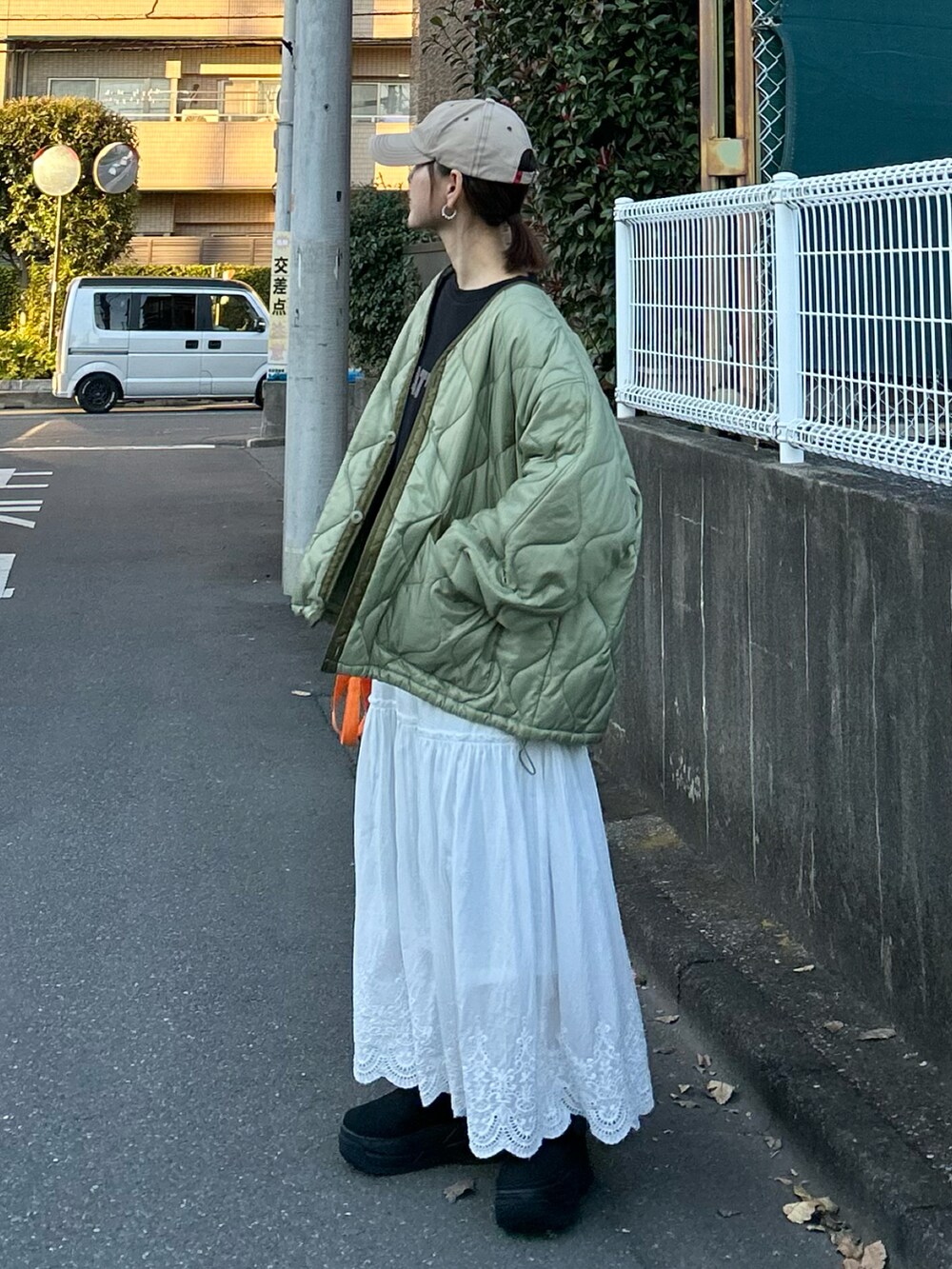 ブラック系のTシャツ/カットソー、グリーン系のノーカラージャケット、ホワイト系のスカートを着用したレディースの冬コーディネートの4枚目の写真
