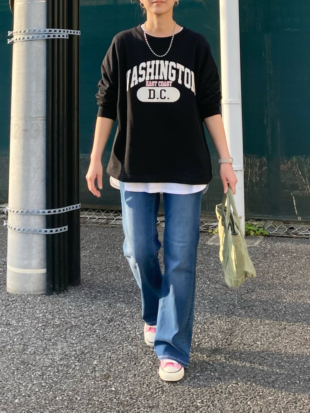 ブラック系のスウェット、ブルー系のデニムパンツ、グリーン系のトートバッグを着用したレディースの春コーディネートの5枚目の写真