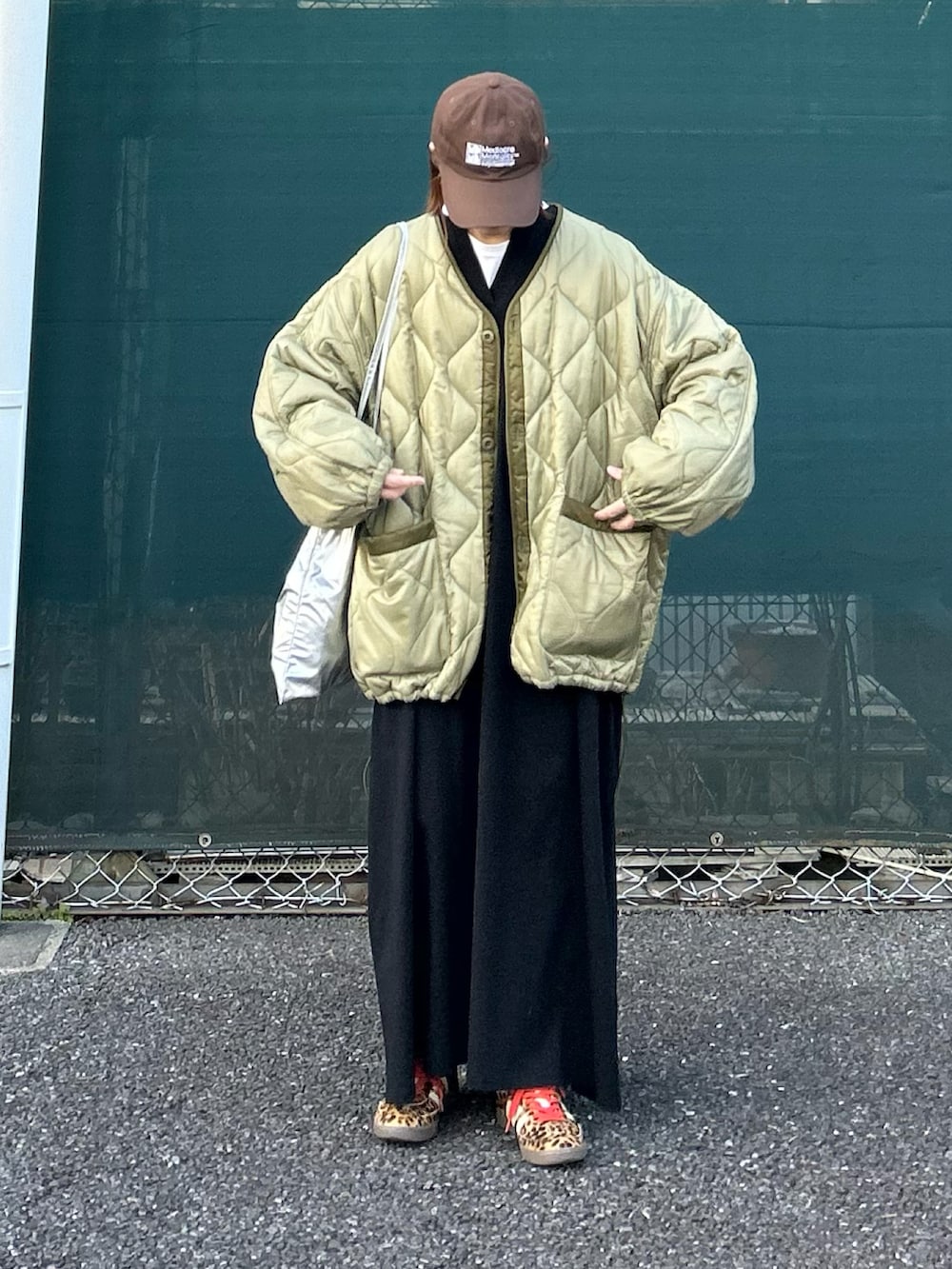 グリーン系のブルゾン、ブラック系のワンピース、シルバー系のクラッチバッグを着用したレディースの冬コーディネートの4枚目の写真