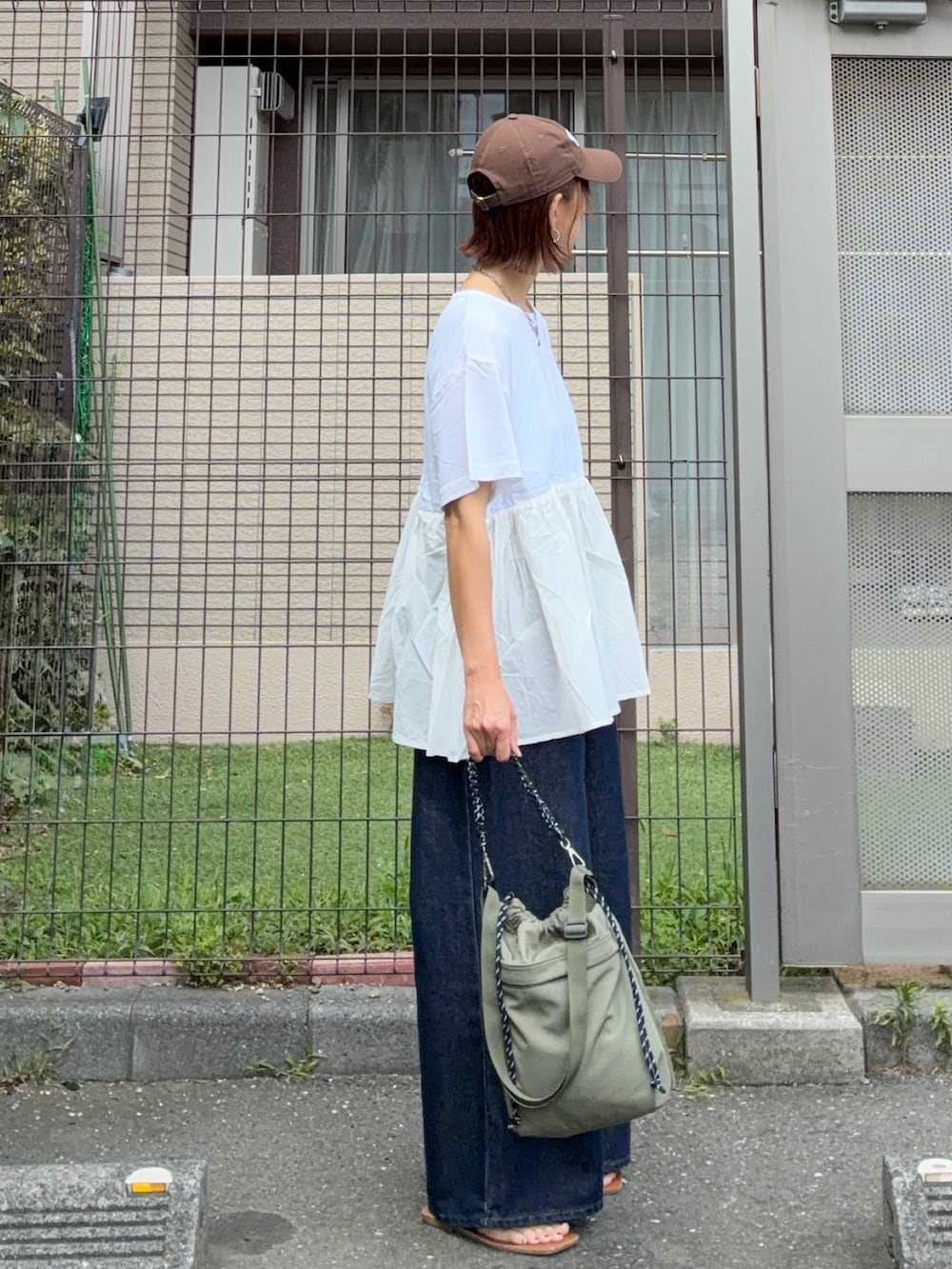 ホワイト系のTシャツ/カットソー、ブルー系のデニムパンツ、グリーン系のショルダーバッグを着用したレディースの夏コーディネートの3枚目の写真