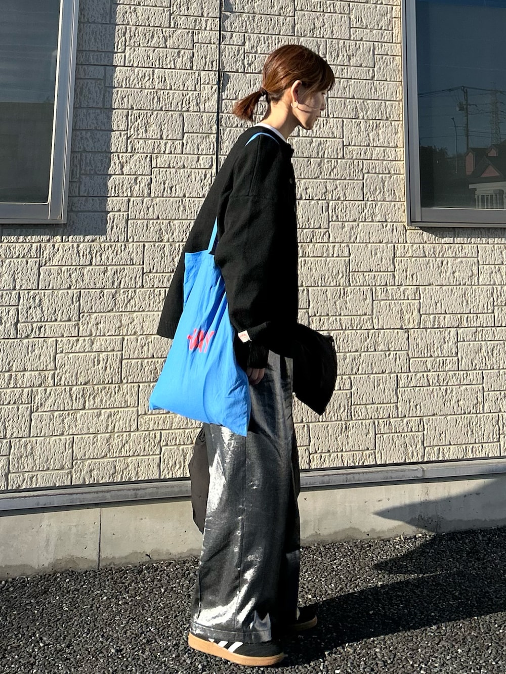 ブラック系のニット/セーター、ブラック系のその他パンツ、ブルー系のトートバッグを着用したレディースの春コーディネートの2枚目の写真