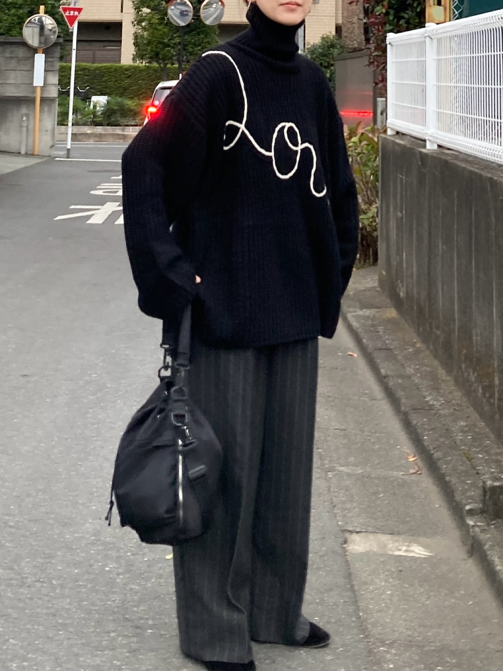 ブラック系のニット/セーター、グレー系のパンツ、ブラック系のショルダーバッグを着用したレディースの冬コーディネートの3枚目の写真