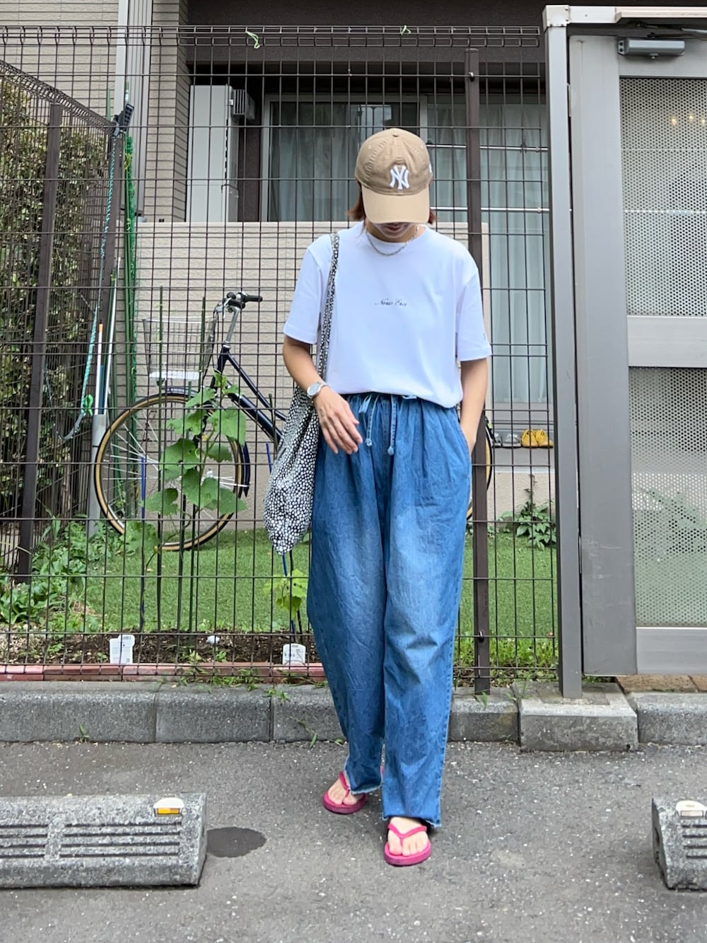 ブルー系のデニムパンツ、ホワイト系のTシャツ/カットソー、パープル系のサンダルを着用したレディースの夏コーディネートの2枚目の写真