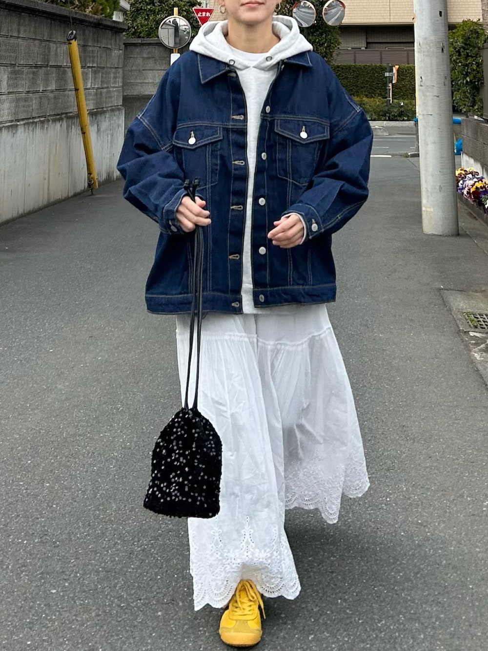 ブルー系のデニムジャケット、グレー系のパーカー、ホワイト系のスカートを着用したレディースの春コーディネートの5枚目の写真