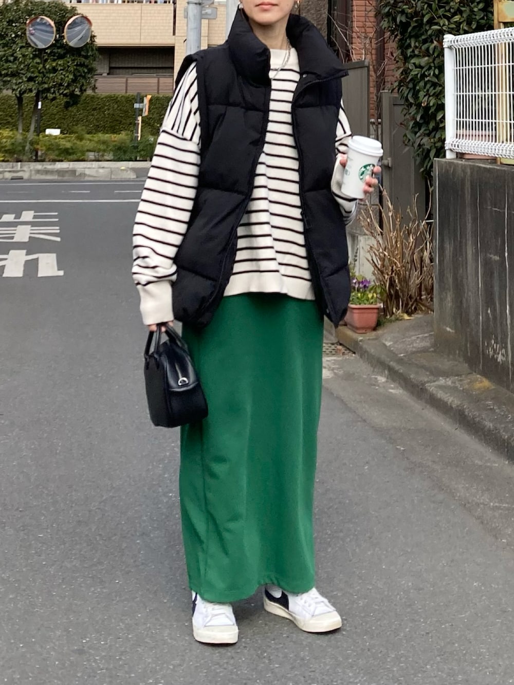 ブラック系のダウンベスト、ホワイト系のニット/セーター、グリーン系のスカートを着用したレディースの冬コーディネートの2枚目の写真