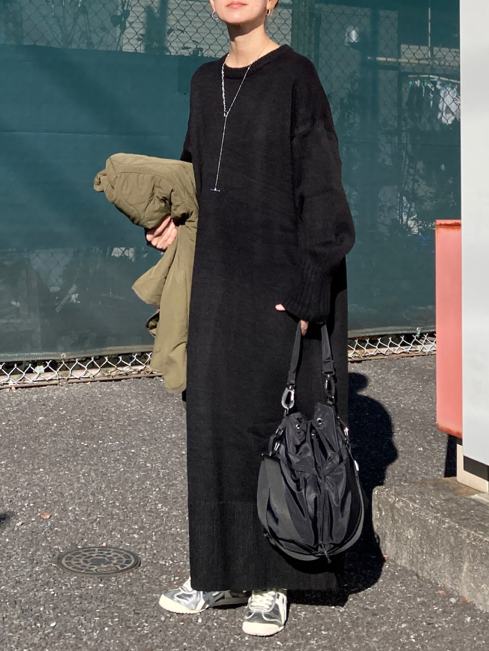 ブラック系のワンピース、ブラック系のショルダーバッグ、シルバー系のスニーカーを着用したレディースの冬コーディネートの2枚目の写真