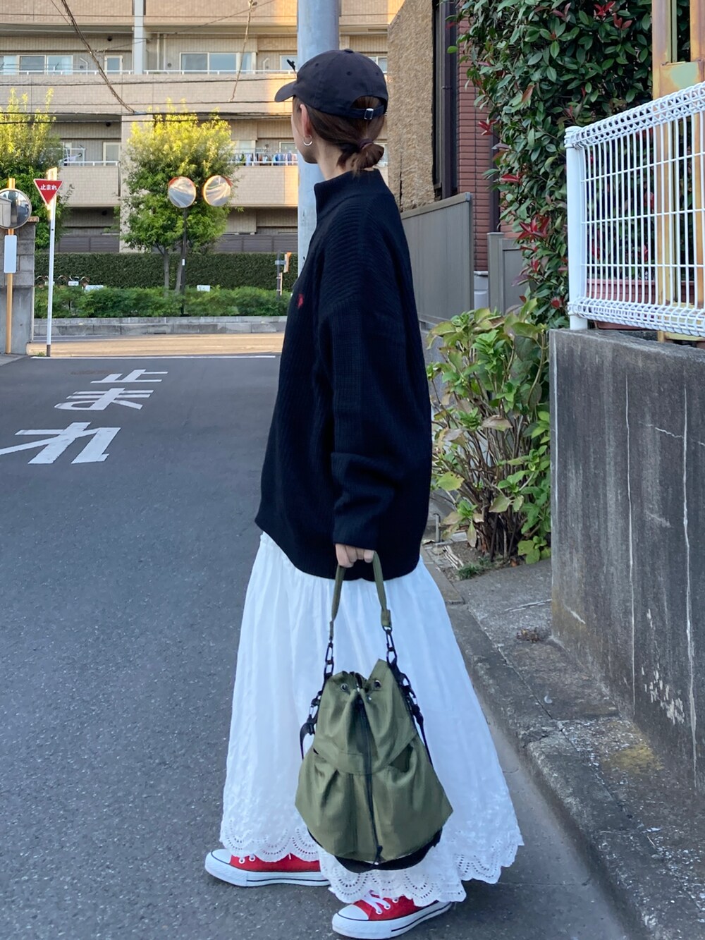 ブラック系のニット/セーター、ホワイト系のスカート、グリーン系のショルダーバッグを着用したレディースの秋コーディネートの4枚目の写真