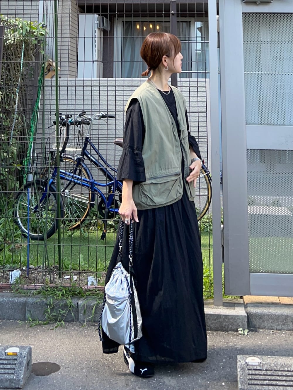 ブラック系のワンピース、シルバー系のトートバッグ、グリーン系のベストを着用したレディースの秋コーディネートの2枚目の写真