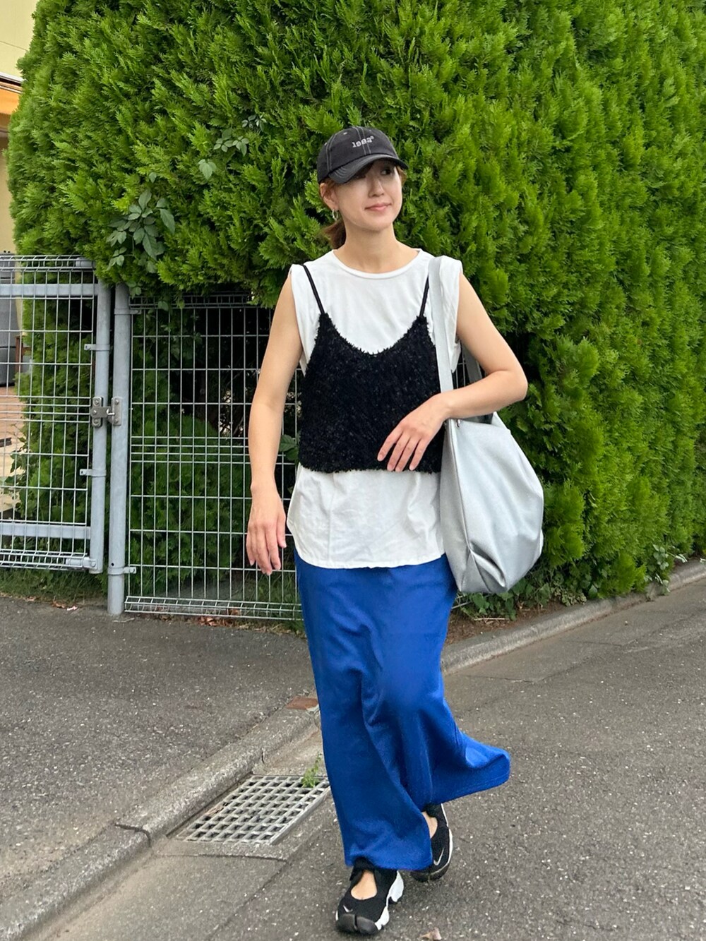 ブラック系のベスト、ブルー系のスカート、シルバー系のショルダーバッグを着用したレディースの夏コーディネートの3枚目の写真