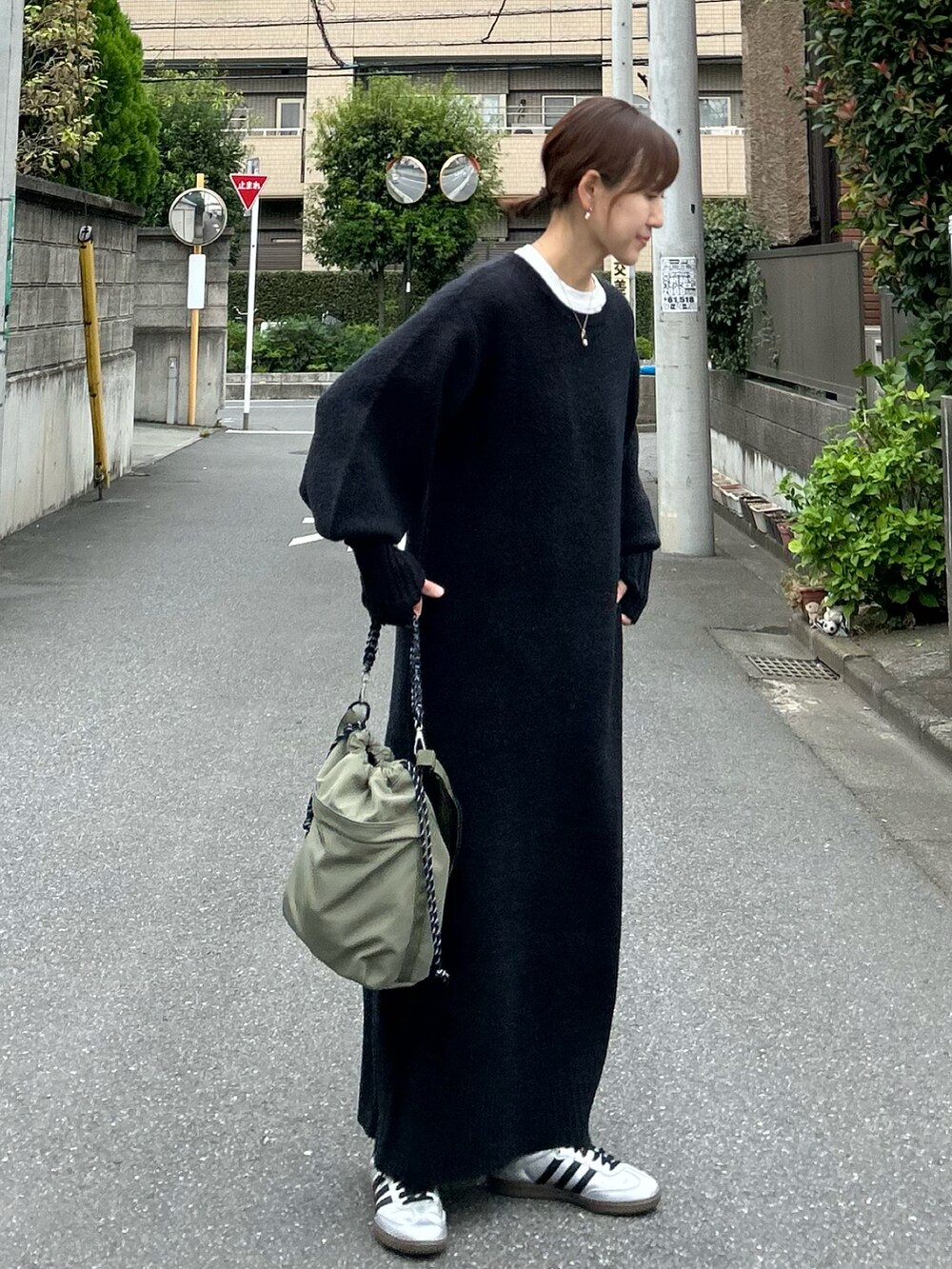 ブラック系のワンピース、グリーン系のショルダーバッグ、シルバー系のスニーカーを着用したレディースの秋コーディネートの5枚目の写真