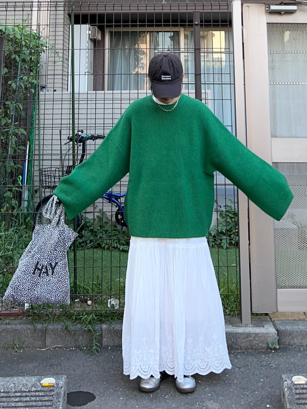 グリーン系のニット/セーター、シルバー系のスニーカーを着用したレディースの夏コーディネートの2枚目の写真