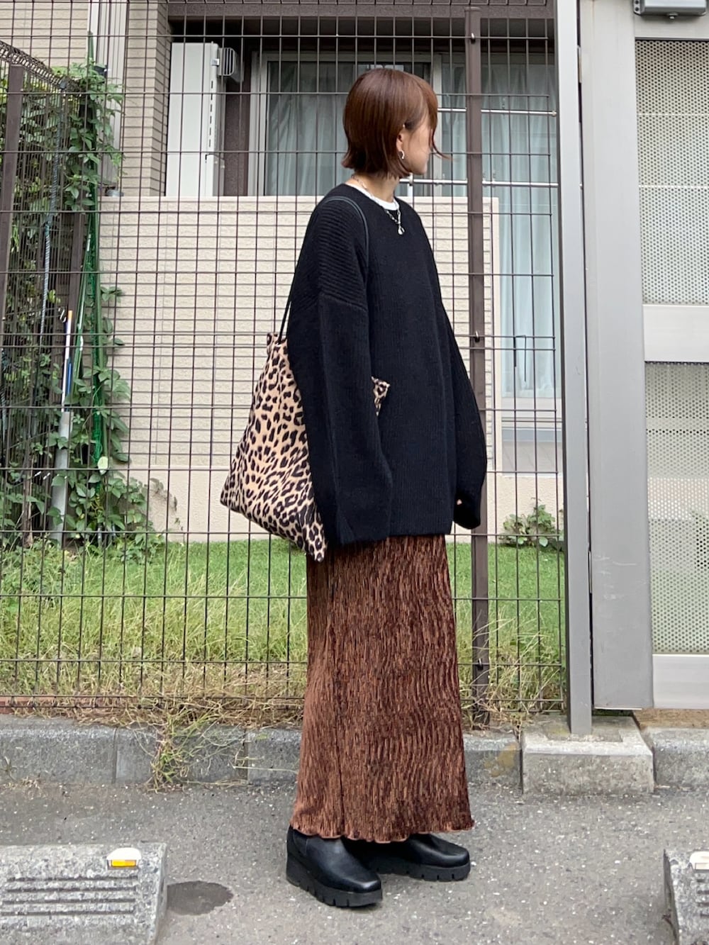 ブラウン系のスカート、ブラウン系のトートバッグ、ブラック系のニット/セーターを着用したレディースの秋コーディネートの4枚目の写真