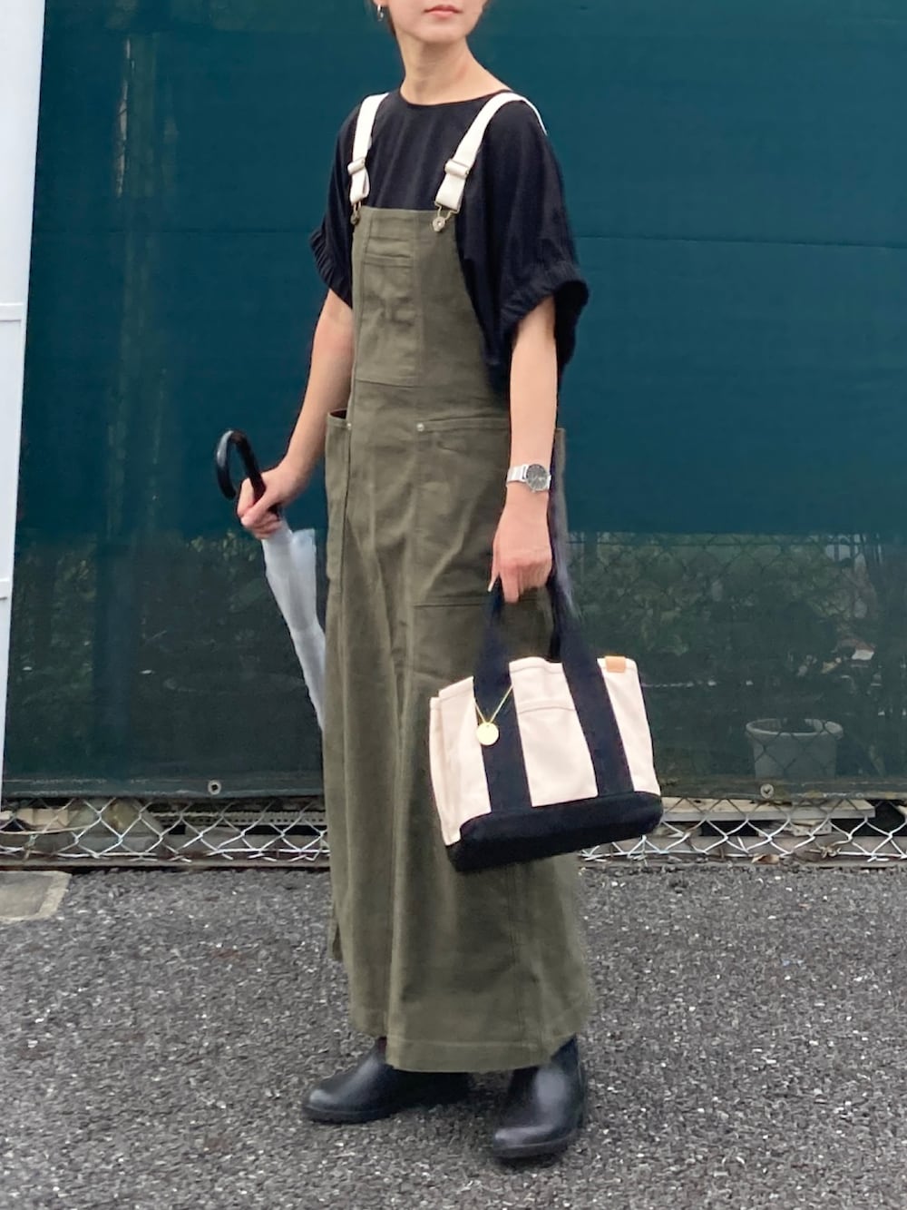 ブラック系のTシャツ/カットソー、グリーン系のジャンパースカート、ホワイト系のトートバッグを着用したレディースの秋コーディネートの2枚目の写真