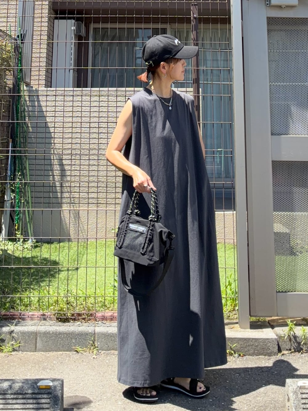 グレー系のワンピース、ブラック系のトートバッグ、ブラック系のキャップを着用したレディースの夏コーディネートの3枚目の写真