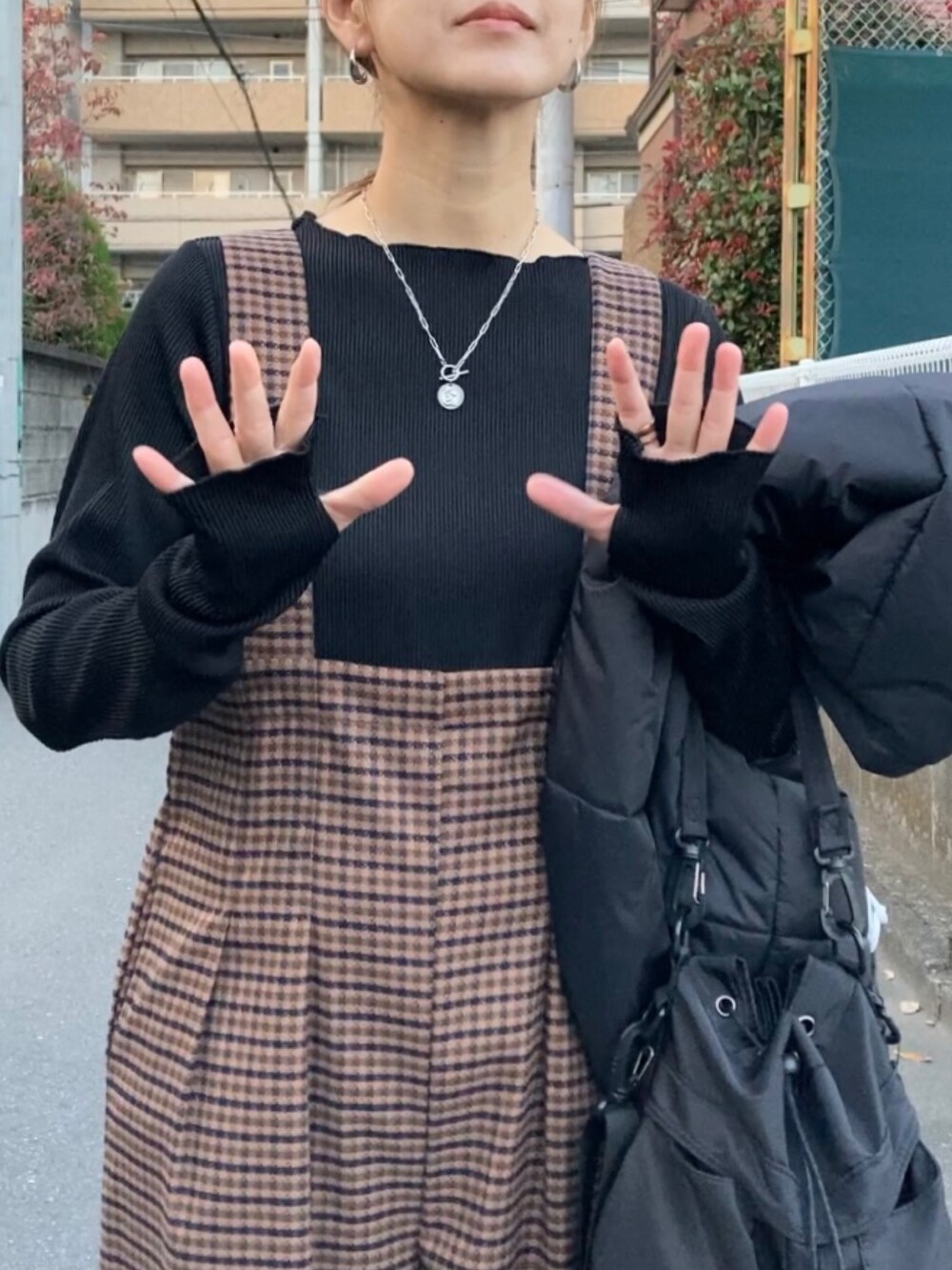 ブラック系のダウンベスト、ブラック系のTシャツ/カットソー、ブラック系のショルダーバッグを着用したレディースの秋コーディネートの5枚目の写真