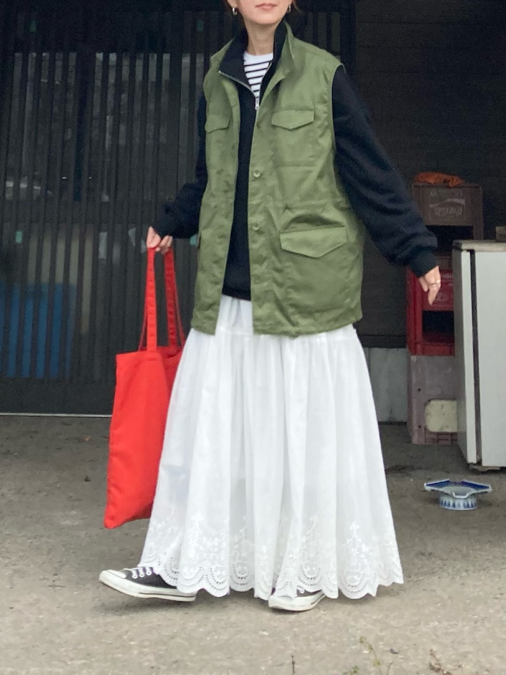 ブラック系のスウェット、グリーン系のベスト、ホワイト系のスカートを着用したレディースの冬コーディネートの2枚目の写真