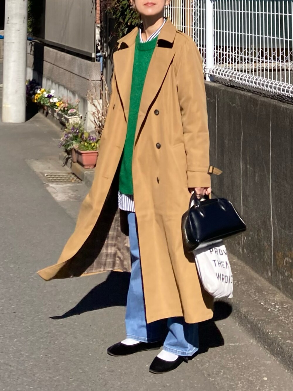 イエロー系のトレンチコートを着用したレディースの冬コーディネートの2枚目の写真