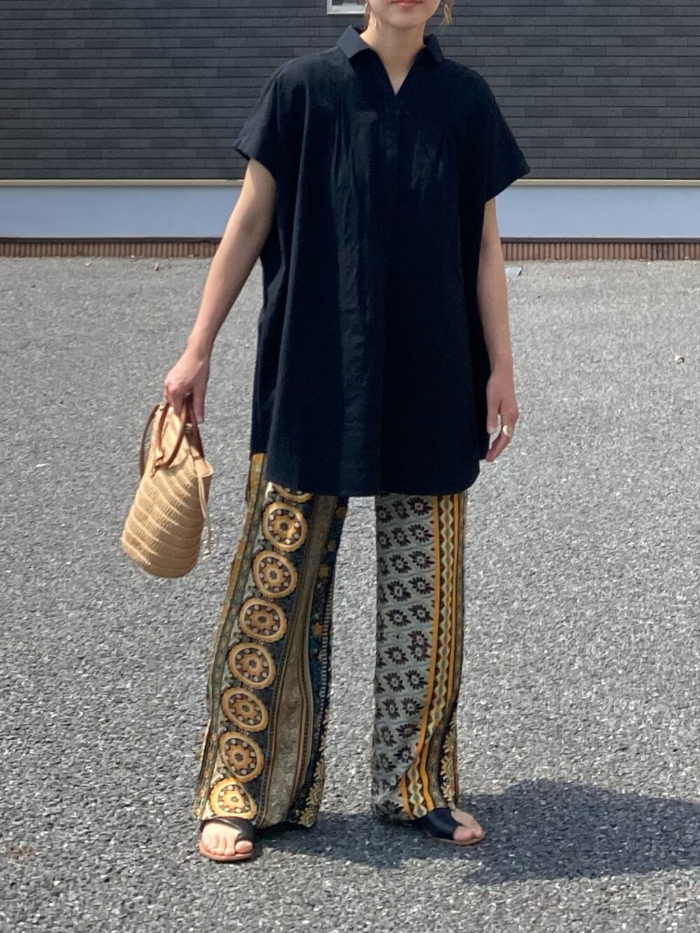ブラック系のその他トップス、イエロー系のその他パンツ、ベージュ系のかごバッグを着用したレディースの夏コーディネートの3枚目の写真