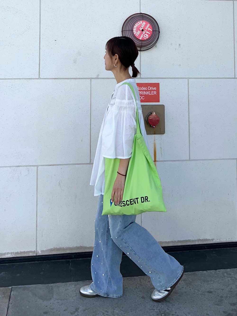 ホワイト系のシャツ/ブラウス、グリーン系のトートバッグ、シルバー系のスニーカーを着用したレディースの春コーディネートの3枚目の写真