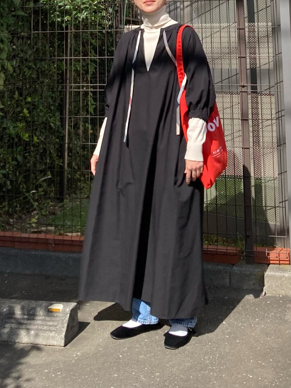 ブラック系のワンピース、レッド系のトートバッグ、ブラック系のパンプスを着用したレディースの秋コーディネートの2枚目の写真