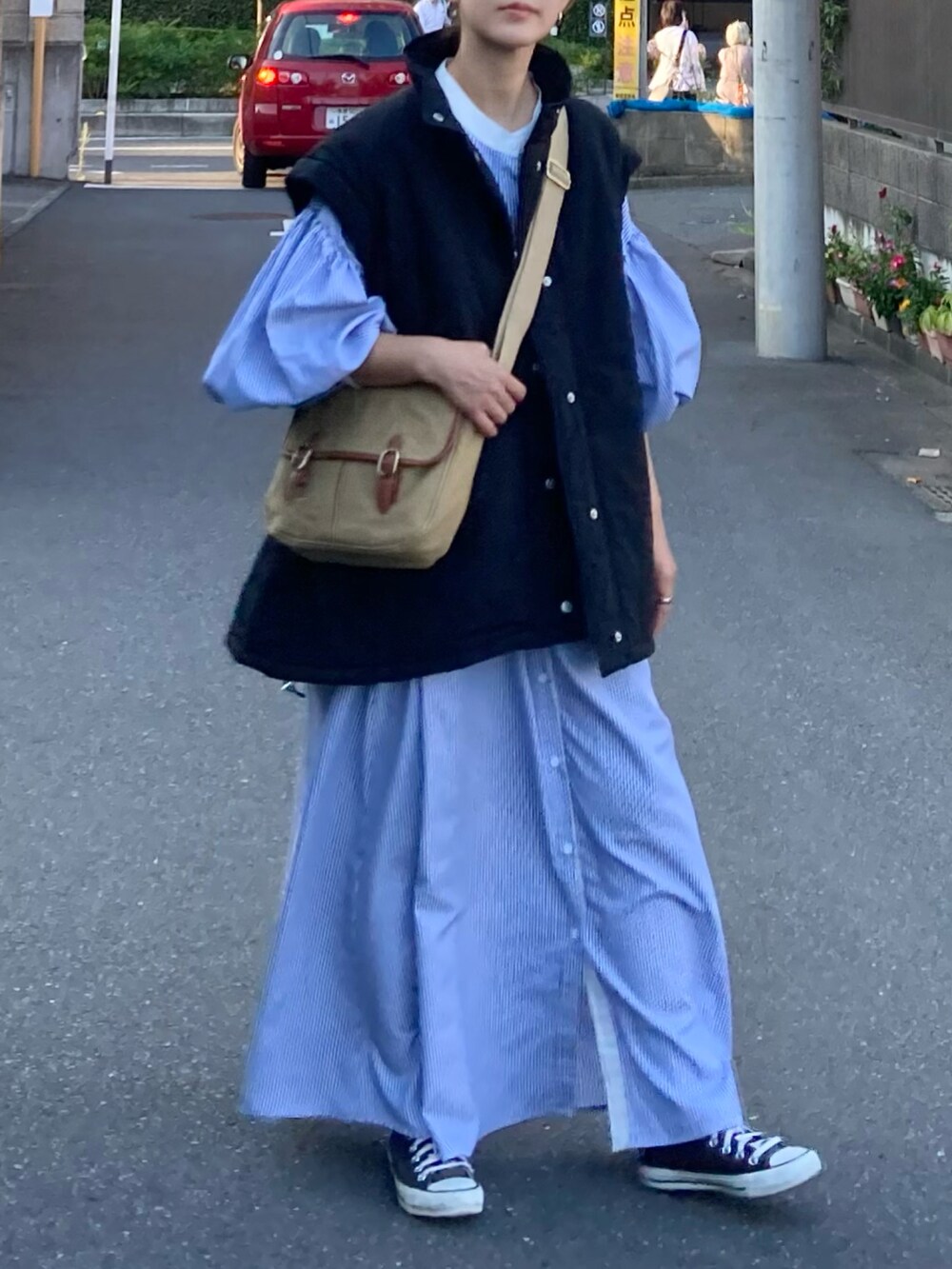 ブラック系のダウンジャケット/コート、ブルー系のワンピース、ベージュ系のショルダーバッグを着用したレディースの秋コーディネートの3枚目の写真