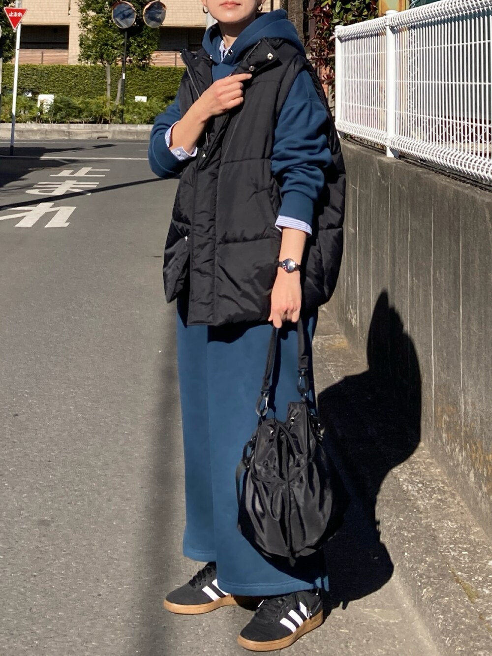 ブラック系のダウンベスト、ブルー系のワンピース、ブラック系のショルダーバッグを着用したレディースの冬コーディネートの3枚目の写真