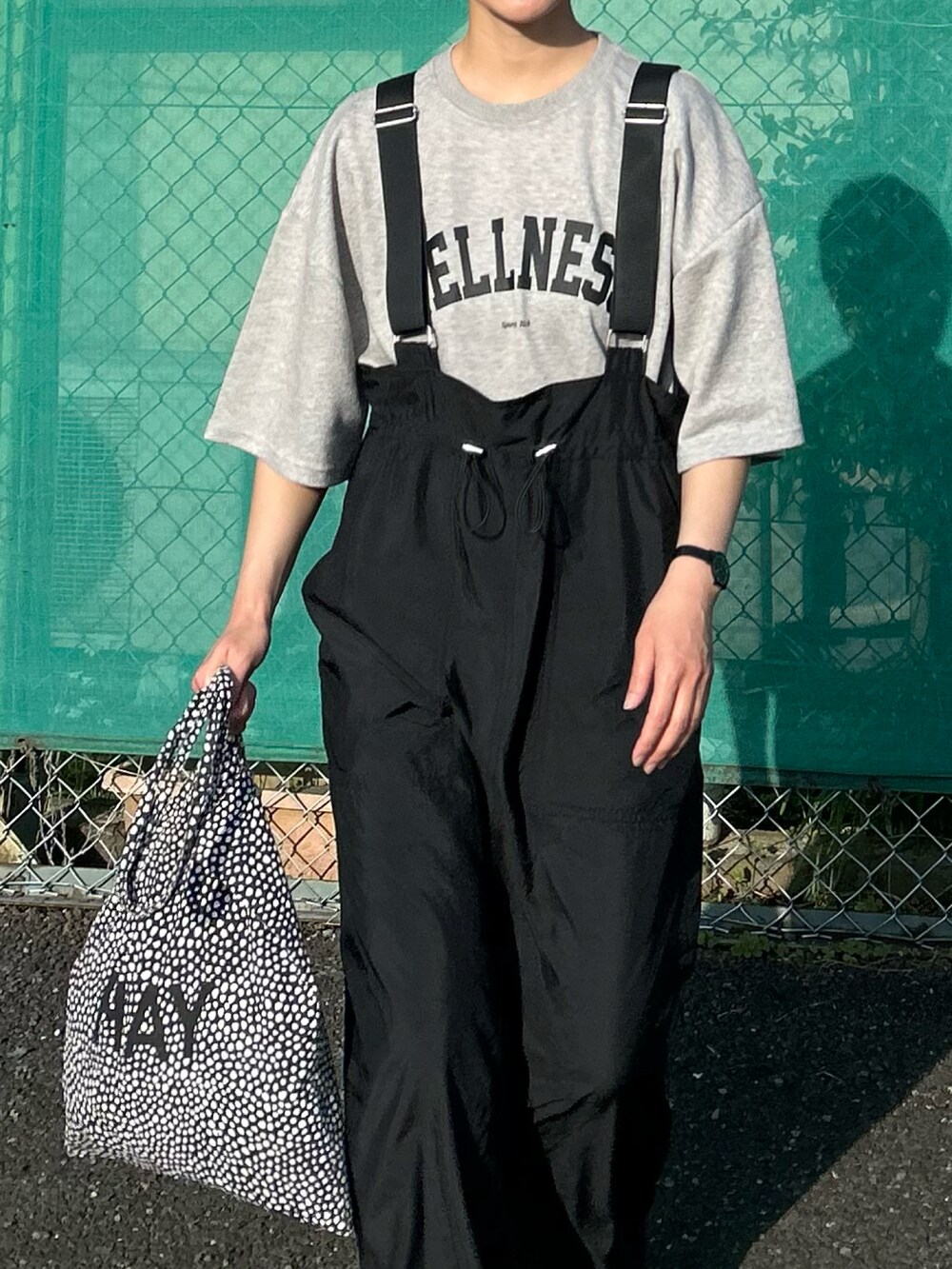 グレー系のTシャツ/カットソー、ブラック系のジャンパースカート、ブラック系のトートバッグを着用したレディースの春コーディネートの5枚目の写真