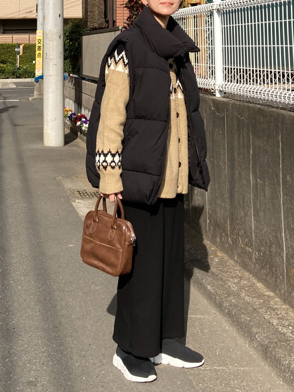 ブラック系のダウンベスト、ベージュ系のニット/セーター、ブラック系のスカートを着用したレディースの冬コーディネートの5枚目の写真