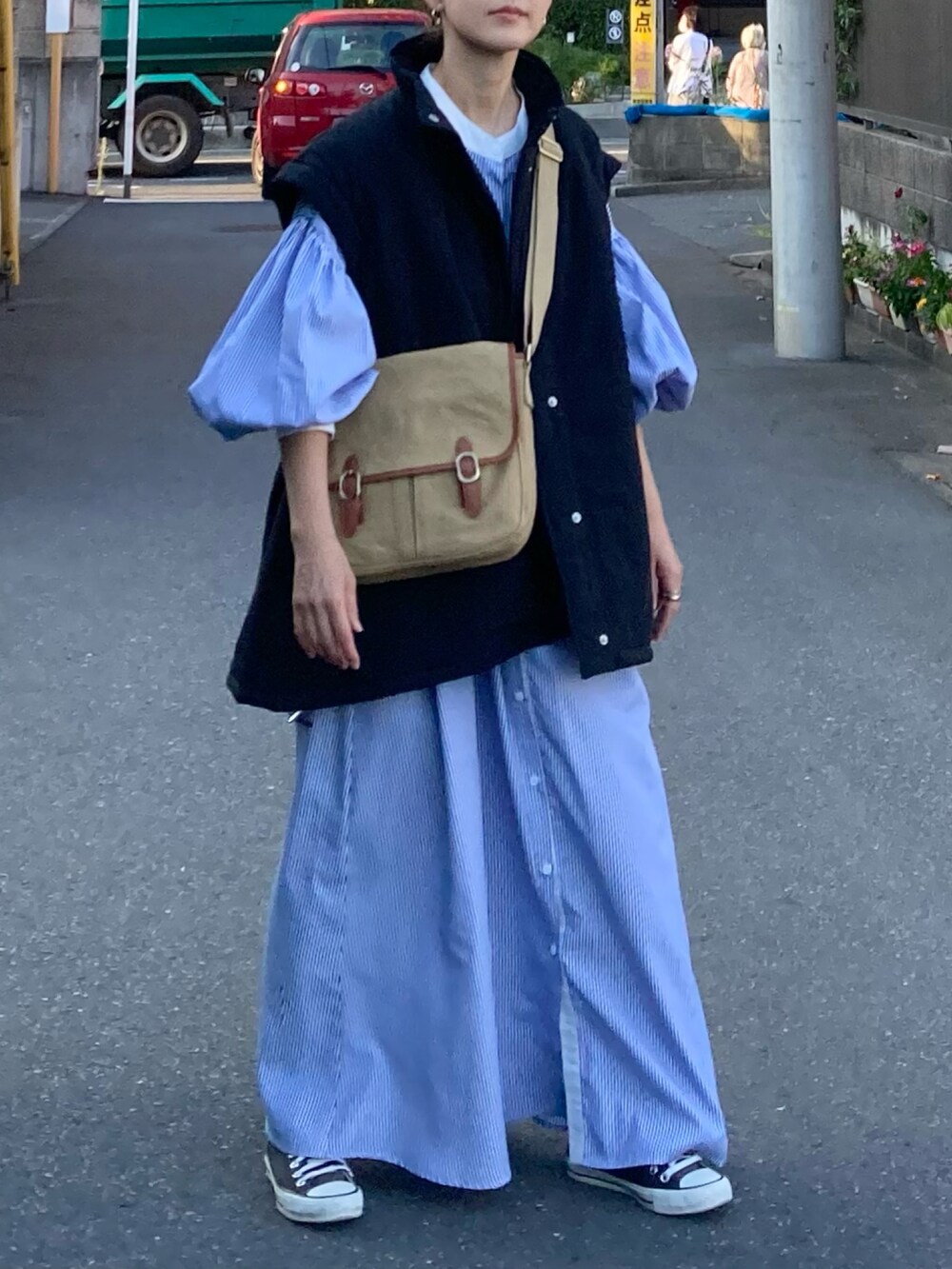 ブラック系のダウンジャケット/コート、ブルー系のワンピース、ベージュ系のショルダーバッグを着用したレディースの秋コーディネートの2枚目の写真