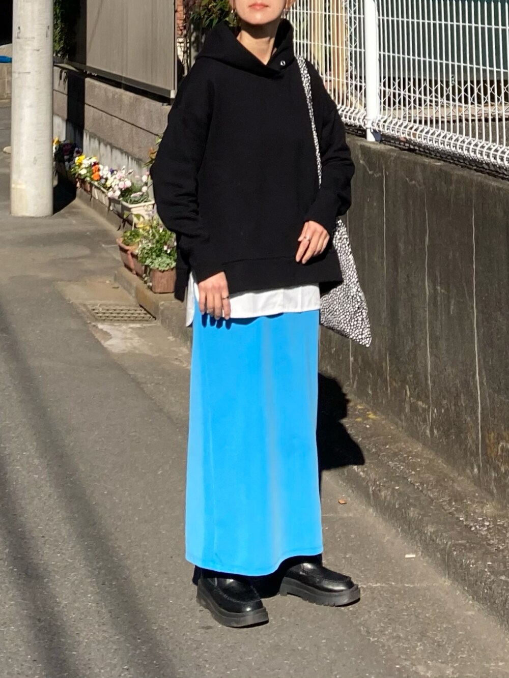 ブラック系のブルゾン、ブラック系のパーカー、ブルー系のスカートを着用したレディースの冬コーディネートの4枚目の写真